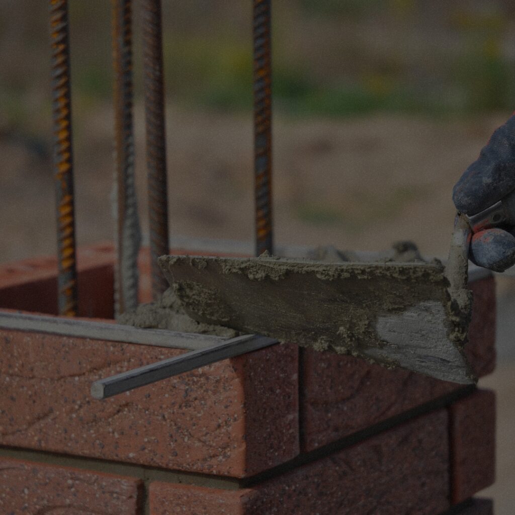 Skilled mason building a durable brick structure with reinforced rebar, specializing in new masonry construction in Seattle Washington.