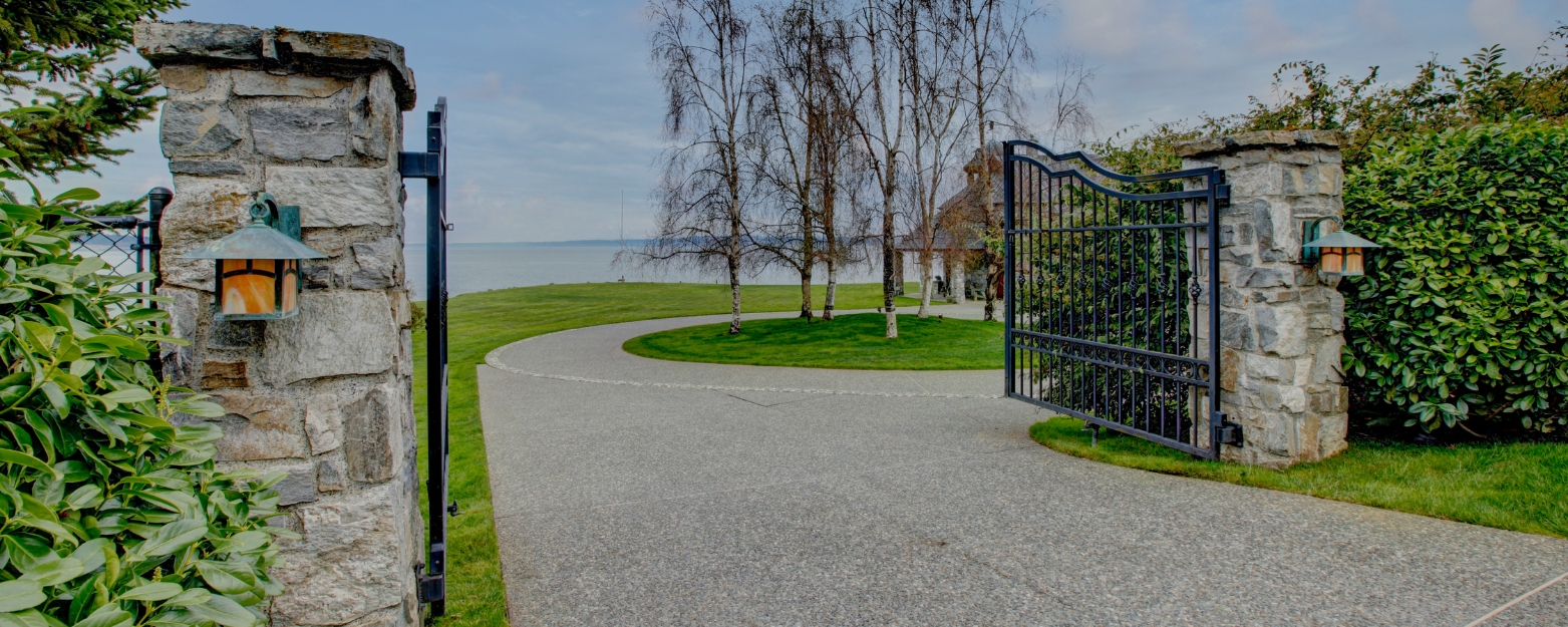 Elegant stone entryway with wrought iron gate, featuring expertly crafted masonry pillars in a waterfront property on Mercer Island, WA.